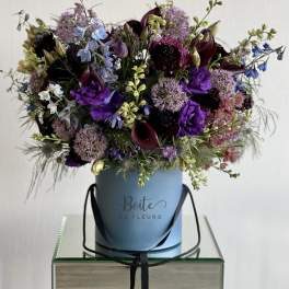 Purple and blue mixed bouquet in a blue hatbox with black ribbon handles