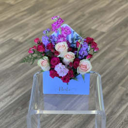 Mixed pink and purple roses arranged in a blue box