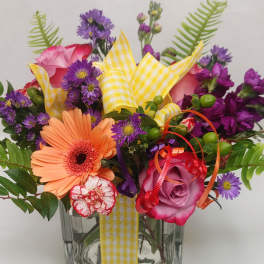 Mixed bouquet in a clear glass vase with pink, purple, and peach flowers
