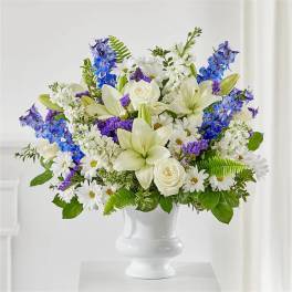 White and blue mixed flower arrangement in a white vase
