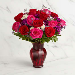 Bouquet of red and pink roses in a red glass vase