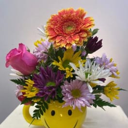 Colorful mixed bouquet in a yellow smiley-face mug