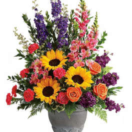 Colorful mixed flower arrangement in a gray vase with sunflowers and roses