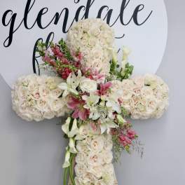 Large floral cross covered in cream roses with pink and white accents