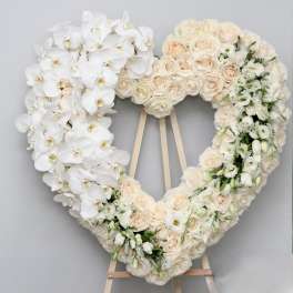 Heart-shaped floral wreath with white orchids and blush roses on an easel