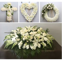 White floral funeral tributes on stands and a large casket spray