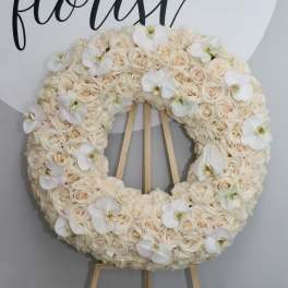 Cream rose wreath with white orchid accents on a wooden easel
