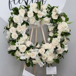 White rose wreath on a wooden easel with greenery