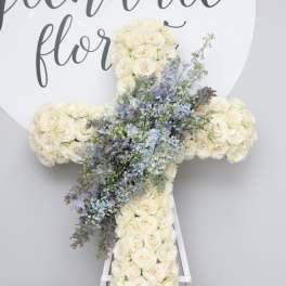 White floral cross on an easel with blue accents