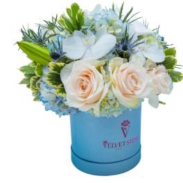 Blue and white floral arrangement in a blue hatbox with roses and orchids