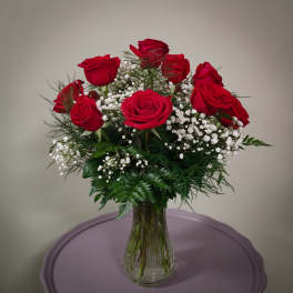 Red roses arranged in a clear glass vase with white baby's breath