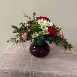 Red roses and white daisies in a round glass vase with a bow