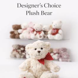 Cream plush teddy bear with red bow and heart on paw, with other teddy bears blurred in the background