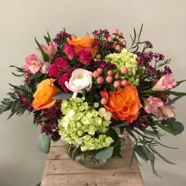 Mixed bouquet of orange and pink roses in a glass vase