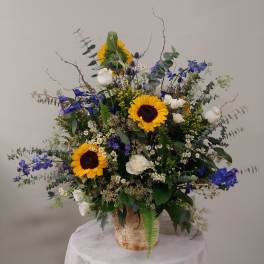 Large mixed bouquet with sunflowers, white roses, and blue flowers in a rustic container