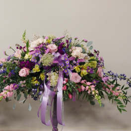 Large pastel floral arrangement in a pedestal vase with trailing blooms