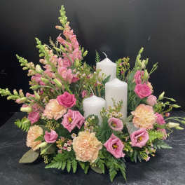 Pink and peach floral centerpiece with three white pillar candles