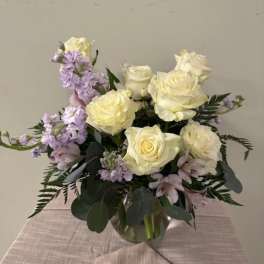 White roses and lavender flowers arranged in a glass vase