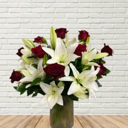 Bouquet of white lilies and deep red roses in a glass vase