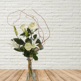 Tall bouquet of white roses and lilies in a clear vase