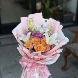 Bouquet of orange roses and white lilies wrapped in pink paper