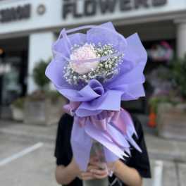 Lavender-wrapped bouquet with a pale pink bloom and baby's breath