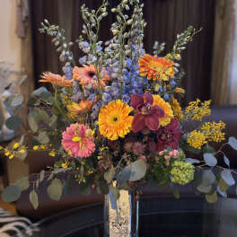 Mixed bouquet in a glass vase with orange, pink, purple, and yellow blooms