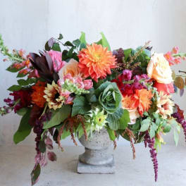 Large mixed flower arrangement in a stone pedestal vase