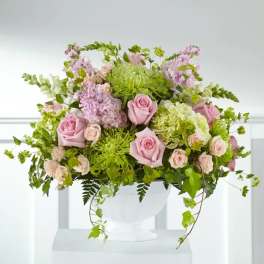 Pink roses and lavender flowers in a white vase