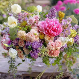 Mixed bouquet of pink, purple, and white flowers in a clear vase