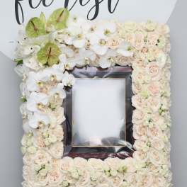 Floral frame of pale roses and white orchids around a photo opening