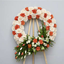 Circular floral wreath of white and orange roses on a wooden easel