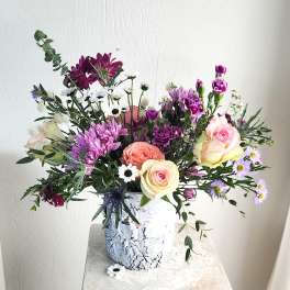 Mixed bouquet of roses, chrysanthemums, and daisies in a white vase