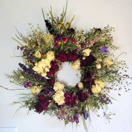 Large circular wreath of dried flowers in cream, burgundy, and purple