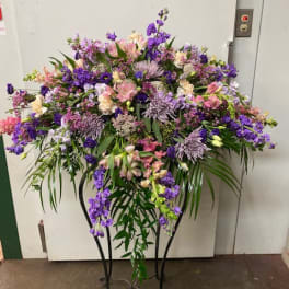 Large purple and pink floral spray on a black metal stand