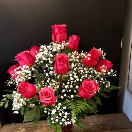 Pink roses arranged with baby's breath in a red vase