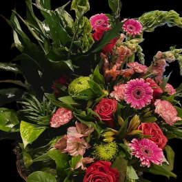 Mixed bouquet with pink gerberas, red roses, and green blooms