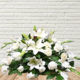 White lily and rose arrangement with green buds on a low base