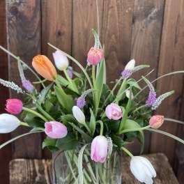 Tulip arrangement in a clear glass vase with pink, white, and orange blooms