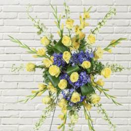 Yellow roses and purple flowers in a standing spray on an easel