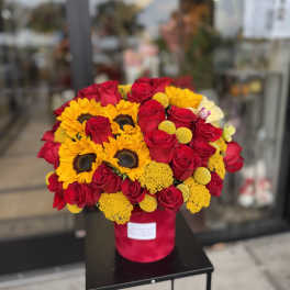 Bouquet of red roses and yellow sunflowers in a red hatbox