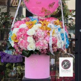 Pink balloon-topped flower arrangement with roses, hydrangeas, and orchids