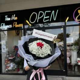 Bouquet of white baby's breath with a single red rose, wrapped in black paper