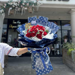Bouquet of red roses wrapped in blue patterned paper with a ribbon