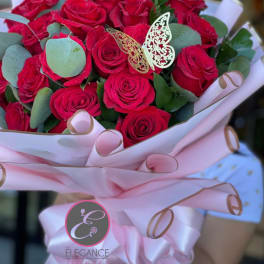 Bouquet of red roses wrapped in pink paper with a butterfly decoration