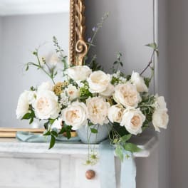 Cream roses arranged in a pale blue vase on a mantel