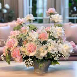 Pink and white roses arranged in a gray vase