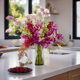 Mixed pink and red orchid arrangement in a glass vase