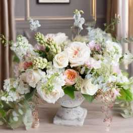Pastel floral arrangement in a stone pedestal vase