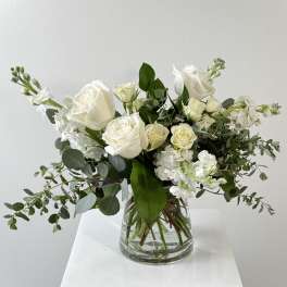 White roses and white stock in a clear glass vase